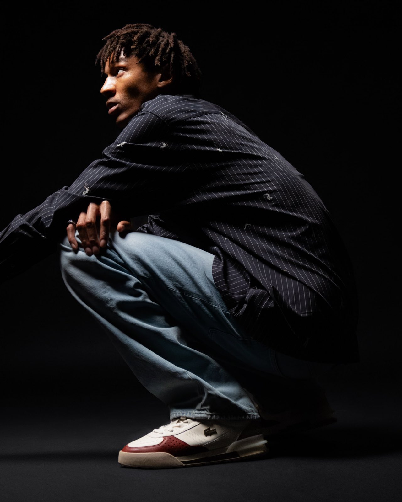 Moody studio portrait in a black cardigan with court sneakers
